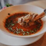 Een kom met bottenbouillon poeder omringd door gezonde ingrediënten, ideaal voor gewrichten en het verminderen van ontstekingen.