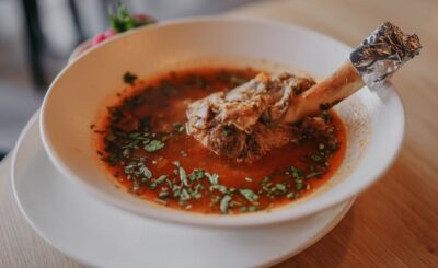 Een kom met bottenbouillon poeder omringd door gezonde ingrediënten, ideaal voor gewrichten en het verminderen van ontstekingen.