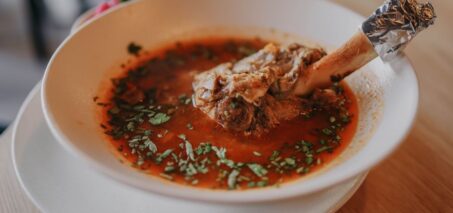 Een kom met bottenbouillon poeder omringd door gezonde ingrediënten, ideaal voor gewrichten en het verminderen van ontstekingen.