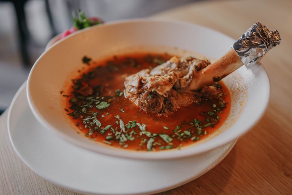 Een kom met bottenbouillon poeder omringd door gezonde ingrediënten, ideaal voor gewrichten en het verminderen van ontstekingen.