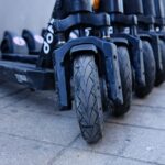 Een moderne brommobiel voor online aankoop, met diverse modellen en kleuren op de achtergrond, geschikt voor verschillende behoeften.